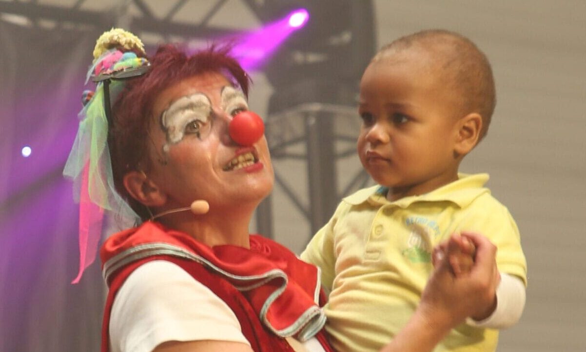 Photo d'Anita le clown. Elle porte un bébé dans ses bras